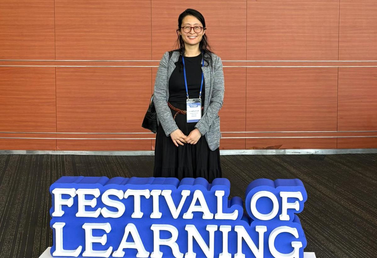 Jonna Lee standing behind a sign that reads "Festival of Learning"